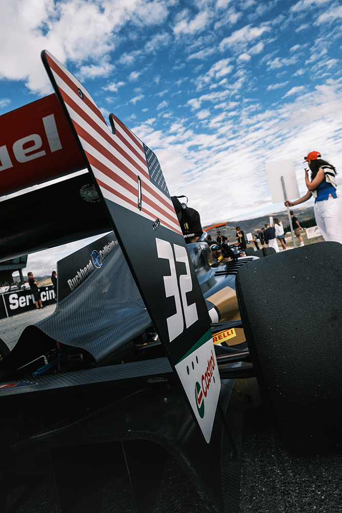 The rear of a black single seater car with the American flag and the number 32 on the side of the rear wing
