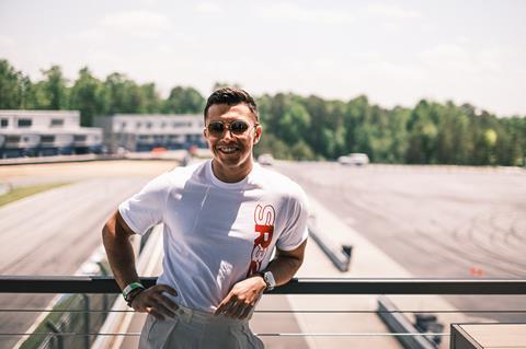 Shawn Rashid posing for a photo while wearing his white branded merchandise with SR23 in red on the front.