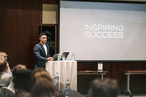 Shawn Rashid stood in front of a podium presenting with the words inspiring success projected behind him